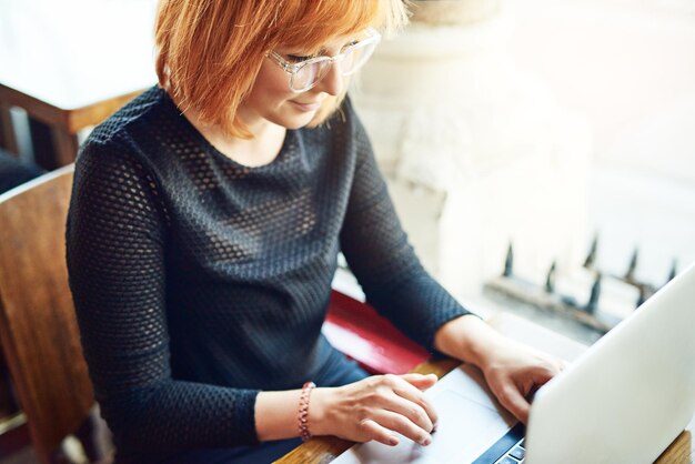 Ich gehe überall hin, wo das Internet kostenlos ist. Schnappschuss einer jungen Frau, die ihren Laptop in einem Café benutzt