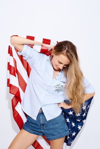 Ich liebe Amerika. Fröhliches Mädchen, das eine amerikanische Flagge auf weißem Hintergrund hält. Das Konzept der Migration und der Nationalfeiertage und des Unabhängigkeitstags der Unabhängigkeit Amerikas 4. Juli