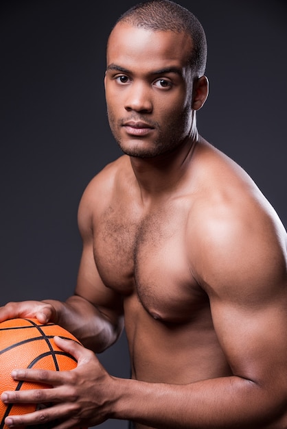 Ich liebe Basketball. Junger afrikanischer Mann mit nacktem Oberkörper, der Basketballball hält und in die Kamera schaut