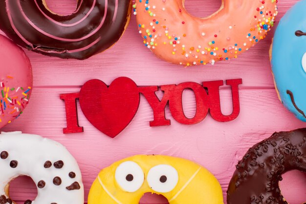 Ich liebe dich Inschrift und Donuts. Süßigkeiten für den Valentinstag. Flache Lay-Komposition.