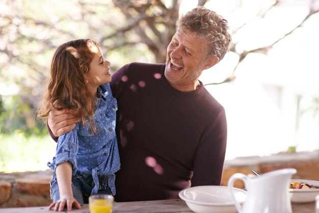 Ich liebe dich so sehr, mein Schatz Aufnahme eines kleinen Mädchens und ihres Großvaters, die draußen zusammen frühstücken