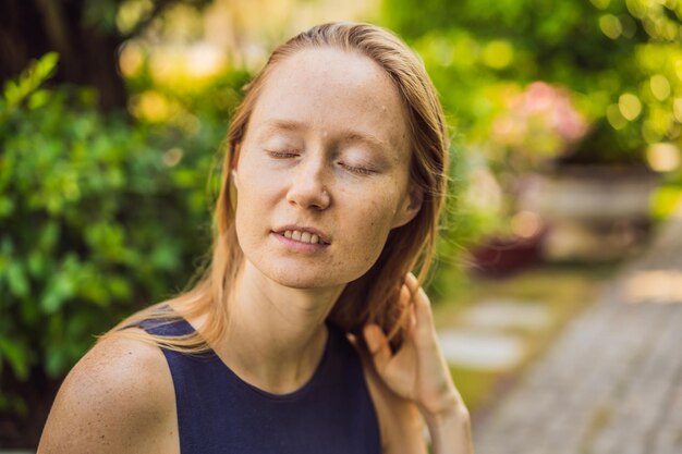 Ich liebe meine Haut Eine junge Frau mit Sommersprossen, Muttermalen, Narben und Gesichtsfalten liebt ihre Haut, genießt das Leben und geht in einem wunderschönen Park spazieren