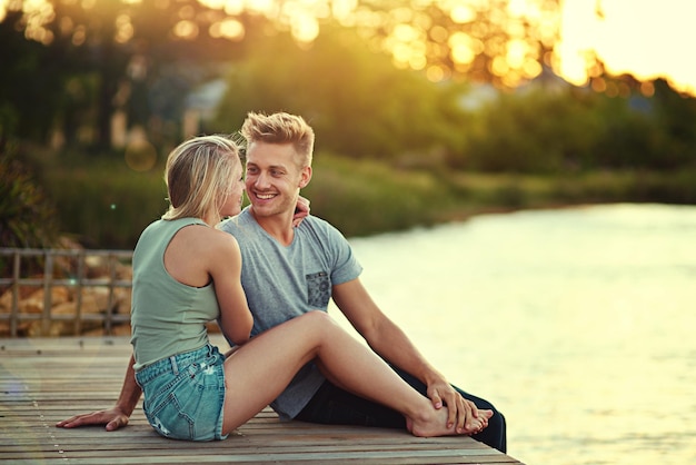Ich möchte alle meine Tage mit dir verbringen Aufnahme eines liebevollen jungen Paares, das draußen an einem See sitzt
