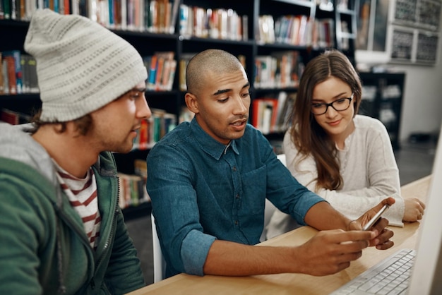 Ich werde diesen Link mit euch teilen Hochwinkelaufnahme von drei jungen Universitätsstudenten, die in der Bibliothek studieren