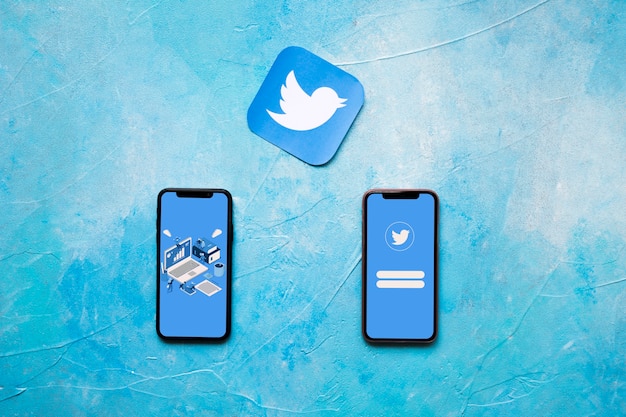 Icono de la aplicación de Twitter y dos teléfonos celulares en la pared pintada de azul