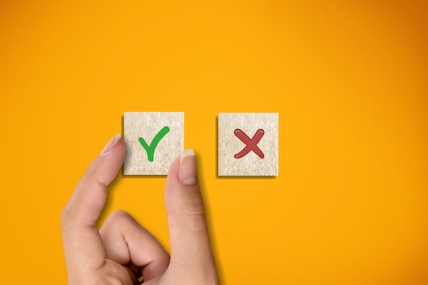 Iconos correctos e incorrectos en cubos de madera con la mano eligiendo el icono correcto