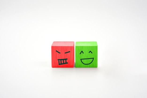Iconos de rostros sonrientes y no sonrientes que imprimen pantalla en un bloque de cubo de madera Concepto de mentalidad emocional
