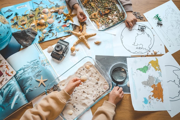 Idea para una actividad con un niño con arena y conchas aprendiendo geografía