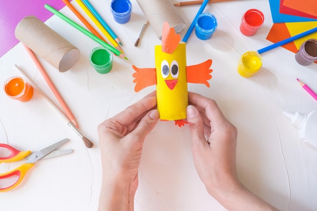 Idea de artesanía de bricolaje fácil de vacaciones para niños Pollito de juguete de tubo de rollo de papel higiénico sobre un fondo blanco