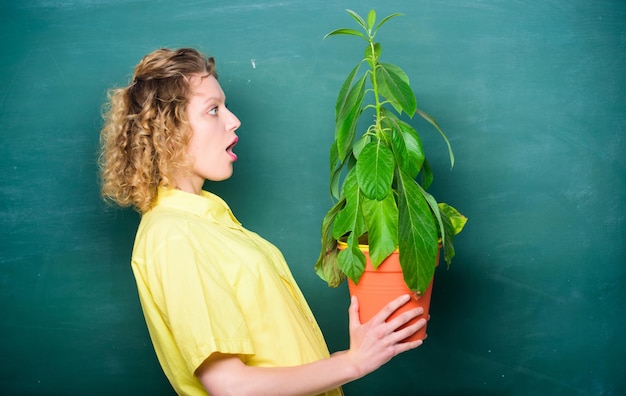 Idea concepto escuela naturaleza estudio sorprendido estudiante niña con planta en pizarra árbol del conocimiento escuela aprendizaje ecología educación ambiental profesor mujer en gafas en lección de biología