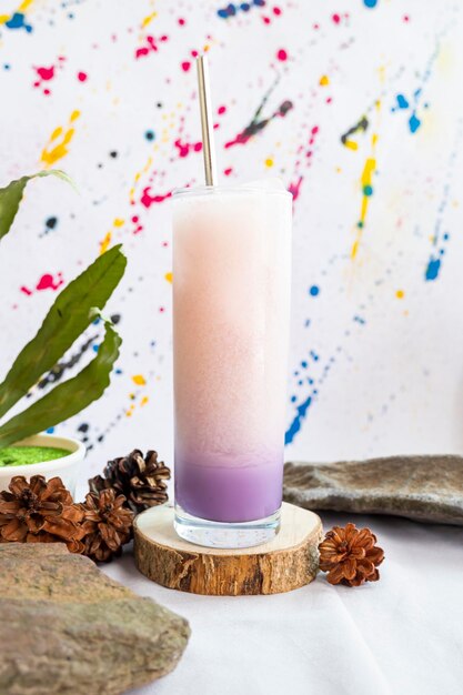 Idea de concepto minimalista. Bebida de hielo de leche de soda púrpura en piedra con hojas verdes sobre fondo abstracto.