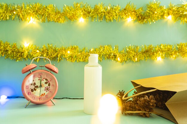 Idea de concepto minimalista que muestra productos. Botellas de cosméticos sobre fondo de Navidad y año nuevo. despertador. flor de pino