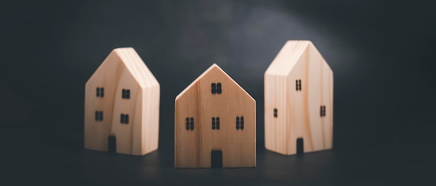 Idea conceptual Modelos de casas de madera sobre la mesa Casa de madera simulada sobre fondo blanco Ideas de negocios de vivienda Casa de juguete hecha de madera colocada sobre un fondo negro con espacio de copia Casas en miniatura