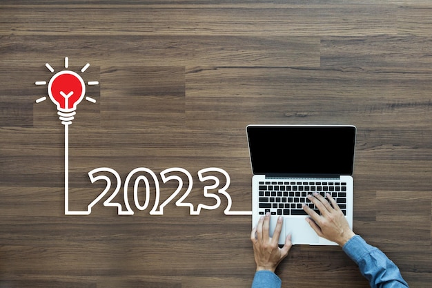 Idea creativa de bombilla 2023 año nuevo Con un hombre de negocios trabajando en una computadora portátil PC Vista superior desde arriba