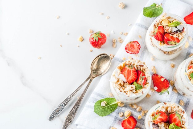 Idea de desayuno saludable, postre casero de parfe en capas en un tarro pequeño con granola, yogur y fresa