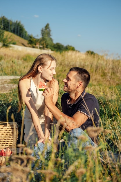 Ideas creativas para citas de verano Picnic romántico Pareja joven enamorada en un picnic de verano con sandía Pareja amorosa en un picnic hablando sonriendo riendo comiendo sandía