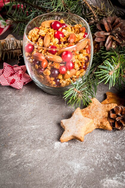 Ideas para un desayuno de invierno, otoño. Acción de Gracias Granola casera de miel fresca cocida con nueces, cacahuetes, avellanas y arándanos. En vidrio, mesa gris,