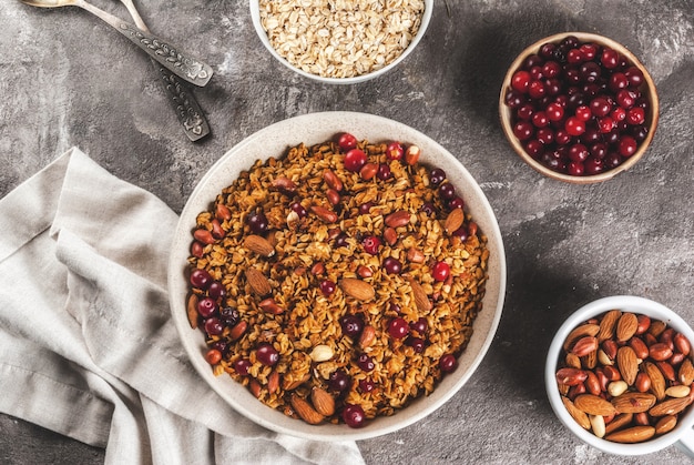 Ideen für ein Winter-, Herbstfrühstück. Das Erntedankfest, . Selbst gemachtes frisches gekochtes Honigmüsli mit Nusssalm, Erdnüssen, Haselnüssen und Preiselbeeren. Auf grauer konkreter Tabelle Draufsicht