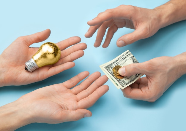 Ideen für Geld verkaufen. Glühbirne als Symbol der Idee. Hände eines Mannes geben eine Idee und nehmen Geld.