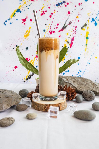 Idéia de conceito minimalista. bebida de leite de café de balgona na pedra com folhas verdes em abstrato.