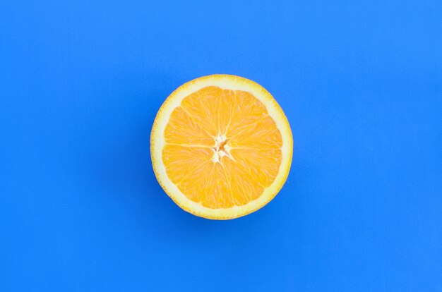 Ideia superior de uma fatia alaranjada de uma fruta no fundo brilhante na cor azul.
