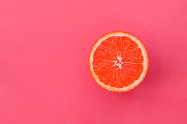 Ideia superior de uma uma fatia da toranja no fundo brilhante na luz - cor cor-de-rosa.