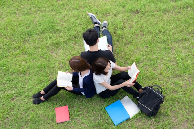 Ideia superior do grupo de estudantes asiáticos que sentam-se junto no parque.