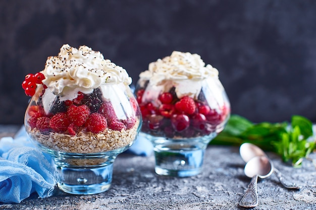 Idéias de receita para o café da manhã da dieta do verão, sobremesa saudável da manhã em potes porcionados com frutas vermelhas do verão - framboesa, cerejas, amora.