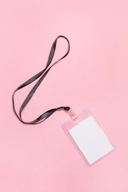 Una identificación de plástico con papel en blanco sobre un fondo rosa.