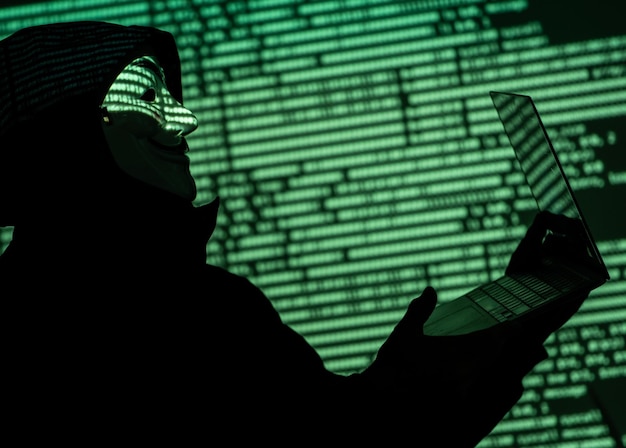 Identitätsdiebstahl mit Kapuze, der einen anonymen Mann mit einer Fawkes-Maske trägt.