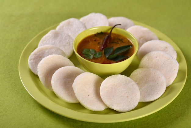 Idli com sambar na tigela sobre fundo verde, prato indiano