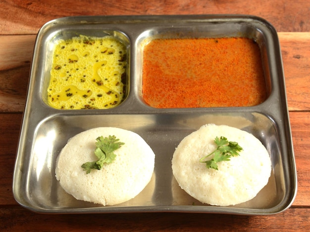 Idli oder idly ist ein gesunder indischer vegetarischer traditioneller und beliebter dampfgegarter Reiskuchen, der mit Schalen mit Chutney und Sambar als Beilagen serviert wird