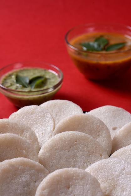 Idli con sambar y chutney de coco sobre fondo rojo, plato indio