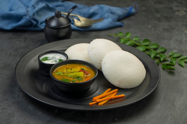 Idly o Idli, artículo principal del desayuno del sur de la India, bellamente dispuesto en un plato negro