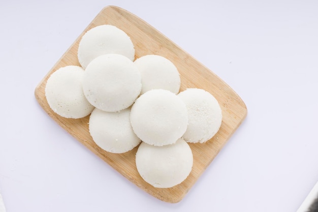 Idly oder Idli südindischer Hauptfrühstücksartikel, der wunderschön in einem Holzsockel mit weißem Hintergrund angeordnet ist