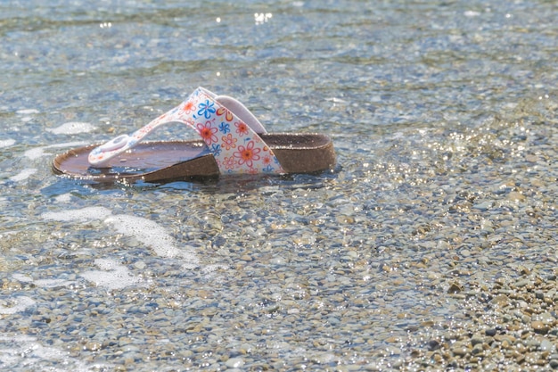 Ido en el océano, el mar, zapatillas de mujer, zapatos perdidos en vacaciones, el concepto del final de las vacaciones, despedirse del mar.