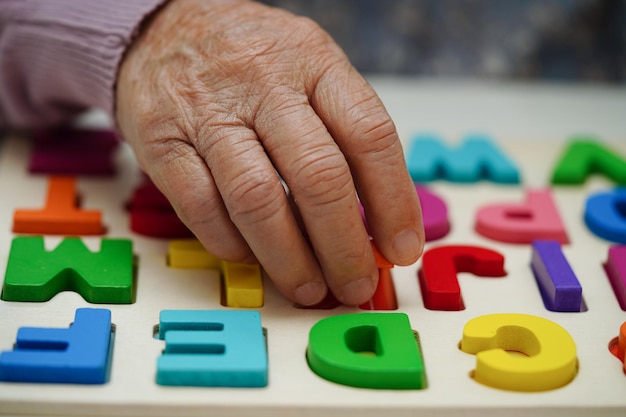 Foto idosa asiática jogando jogo de quebra-cabeças para praticar treinamento cerebral para prevenção de demência doença de alzheimer