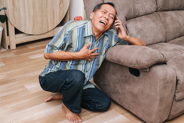 Foto idoso asiático agarrando o peito esquerdo de dor aguda enquanto faz um telefonema pedindo ajuda