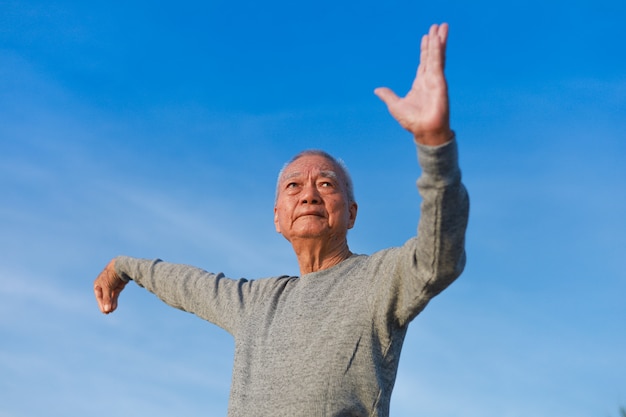Foto idoso asiático praticando taichi chinês kungfu na praia