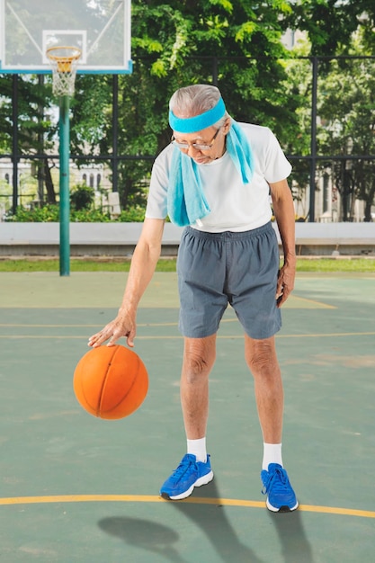 Foto idoso dribla uma bola de basquete na quadra de basquete