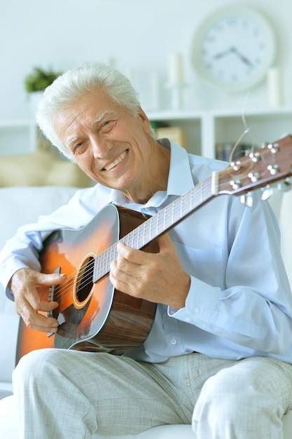 Idoso feliz com guitarra em casa