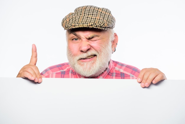 Idoso. Homem barbudo sênior emocional espreitar fora do anúncio de lugar de banner. Avô aposentado no espaço da cópia de informações do cartaz de chapéu vintage. Conceito de anúncio. Anúncio do evento.