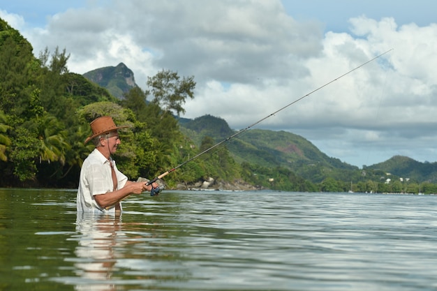 idoso pescando no mar com uma vara de pescar