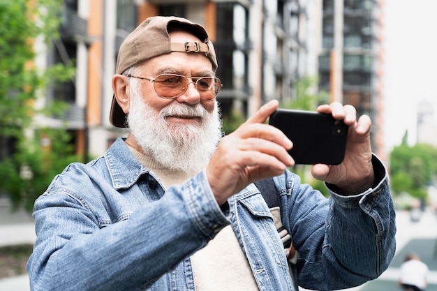 Idoso usando smartphone para selfie ao ar livre na cidade