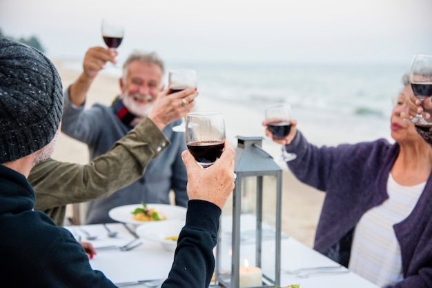 Idosos brindando com vinho tinto na praia