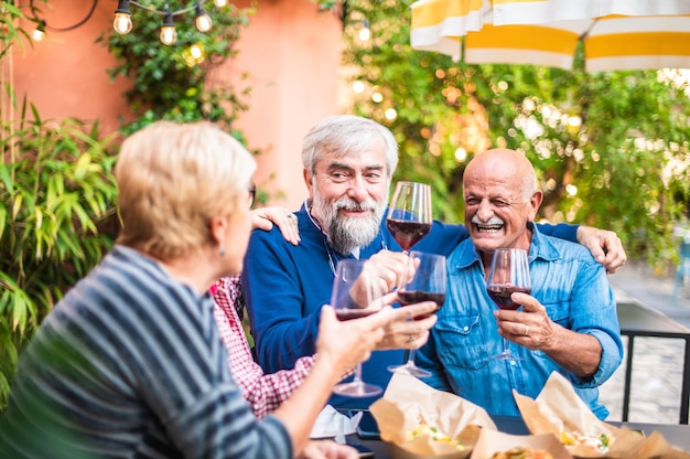 Foto idosos brindando vinho em restaurante bar