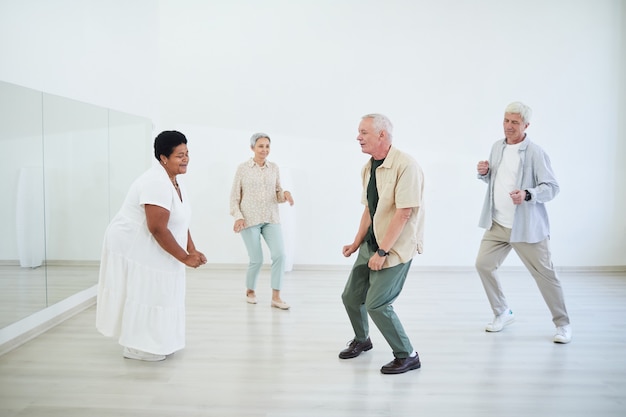 Idosos fazendo aulas de dança em um estúdio de dança, curtindo a dança e a música