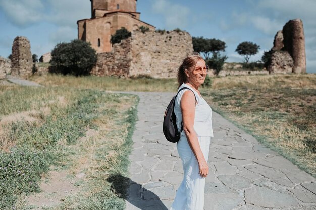 Idosos felizes viajando mulher madura mochileiro turista ao ar livre na europa antiga ruínas de fortalezas pessoas aposentadas férias de verão conceito de estilo de vida ativo mosteiro de jvari mtskheta geórgia