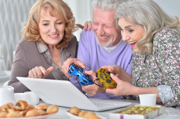 Idosos jogando jogo de computador com laptop enquanto bebe t