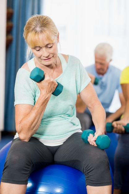 Idosos usando bola de exercícios e pesos